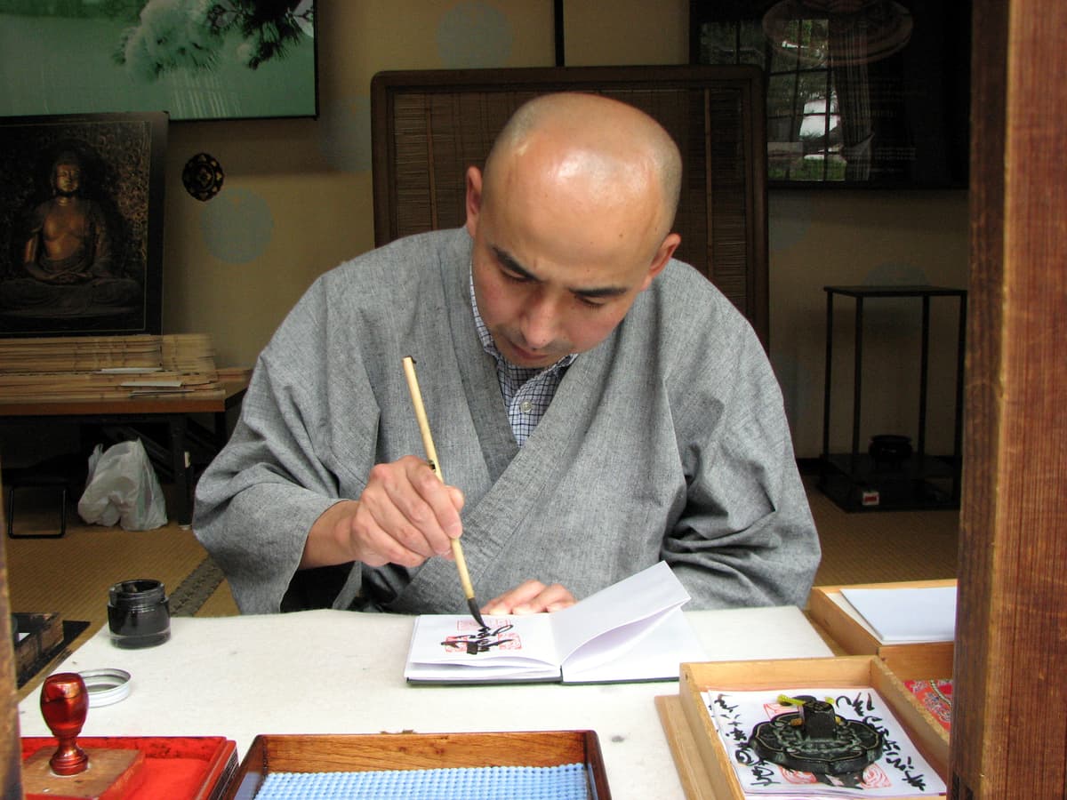 Ein Mönch schreibt 2006 im Byodo-in einen Goshuin in ein offenes Buch