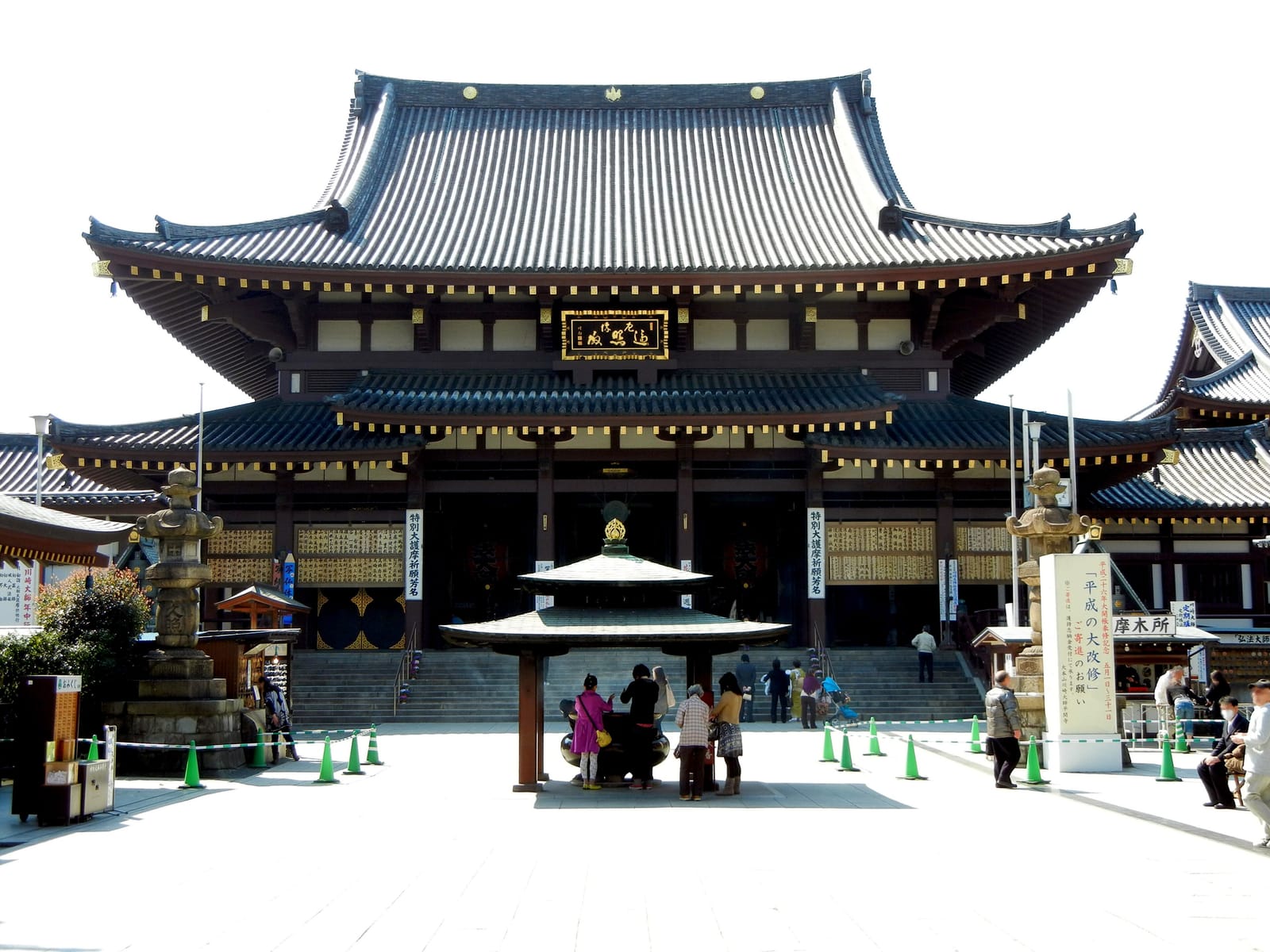 Visitantes se aproximam do salão principal e do queimador de incenso em Kawasaki Daishi
